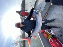 A person holding a large paddlefish on a boat 