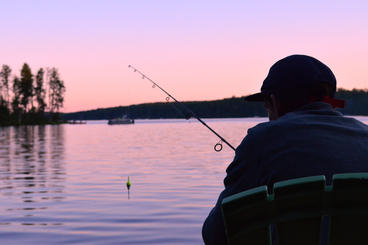 A person fishing on a lake at sunset. 