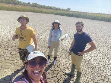 Four people standing in a dried up marsh